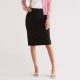A woman wearing a white top, pink cardigan, black skirt, and white kitten heels