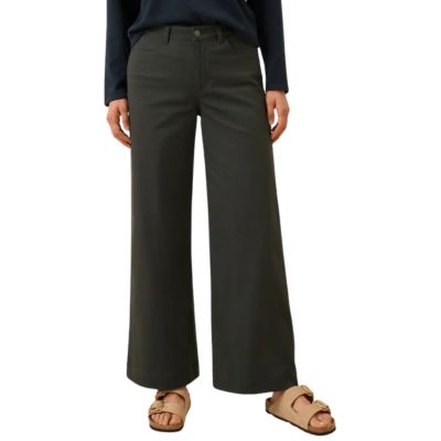 A woman (lower half of body) wearing dark brown pants and light brown sandals