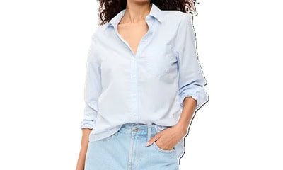 A woman wearing a light blue button-front shirt and light blue denim shorts