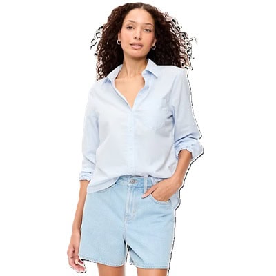 A woman wearing a light blue button-front shirt and light blue denim shorts