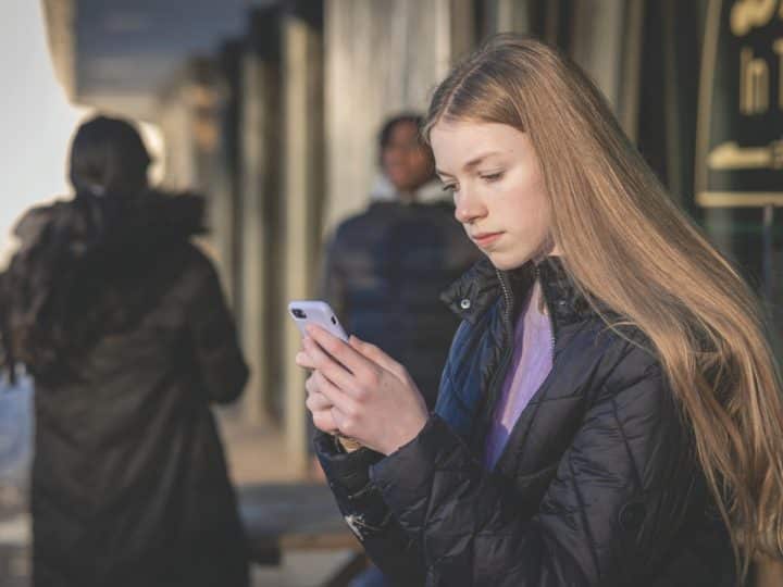 A girl looks at a mobile phone Online misogyny Barnardo's