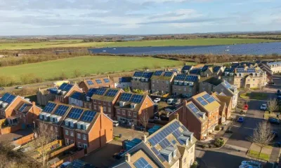 Illustrative image of houses with solar panels and a solar farm in the background Fairer pricing through renewable energy