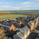 Illustrative image of houses with solar panels and a solar farm in the background Fairer pricing through renewable energy