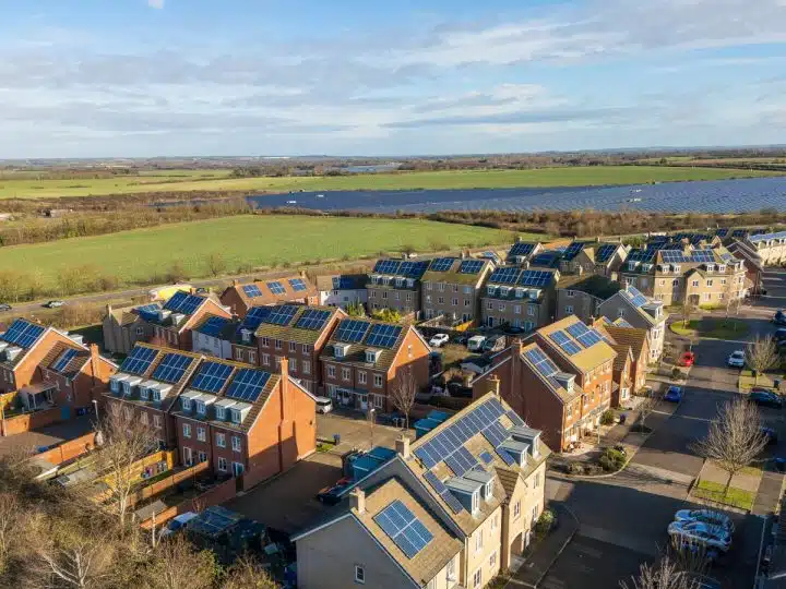 Illustrative image of houses with solar panels and a solar farm in the background Fairer pricing through renewable energy