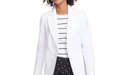 A woman wearing a white blazer, white-and-black striped top, and white-and-black polka dots pants