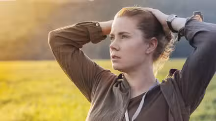 Amy Adams looking to the distance with her hands on her hair in Arrival