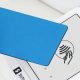 person holds blue credit card at a payment station (tap to pay)