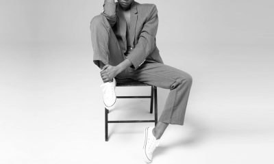 professional woman wears a suit and sneakers; she is sitting on a chair with one leg drawn up.