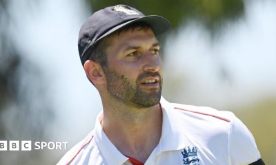 Mark Wood, wearing a blue England cap, looks to the side