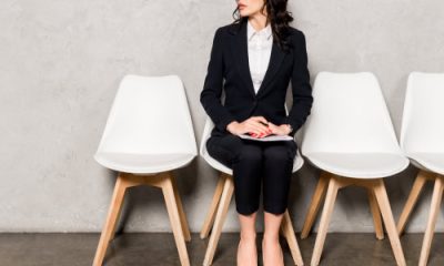 professional woman wearing a budget-friendly interview suit for women waits for her interview; she might be a college student, grad school student, or law school student