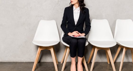 professional woman wearing a budget-friendly interview suit for women waits for her interview; she might be a college student, grad school student, or law school student