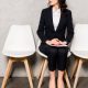 professional woman wearing a budget-friendly interview suit for women waits for her interview; she might be a college student, grad school student, or law school student
