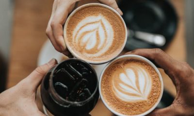 friends toast with lattes and another dark drink that is possibly soda or cold brew