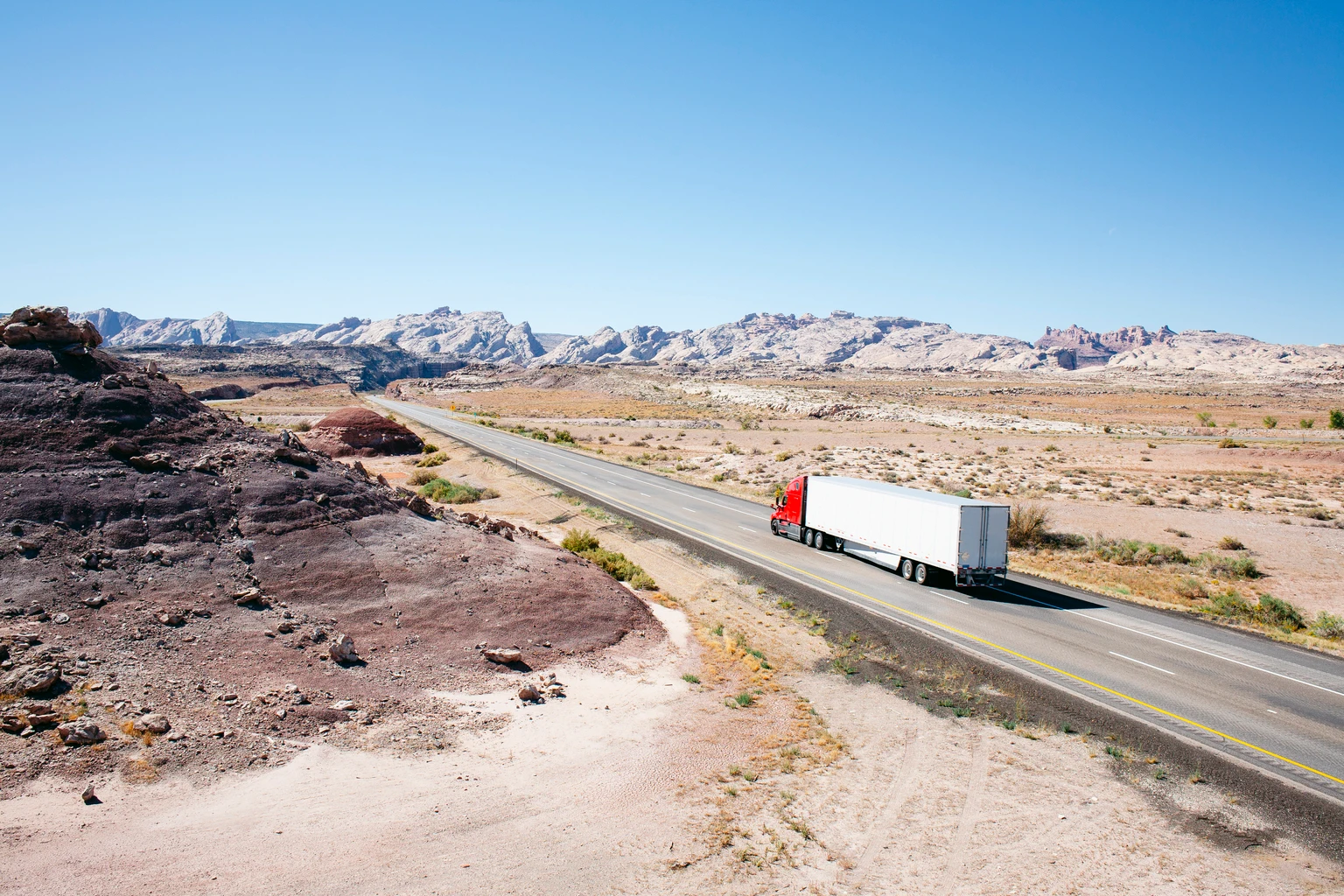 Truck on a desert road leading into the distance