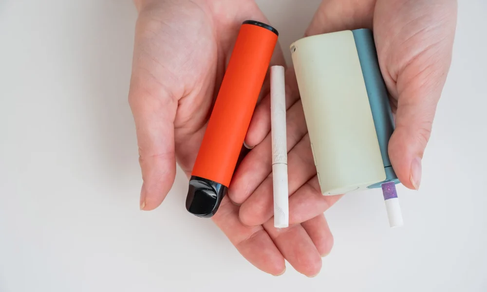 Woman holding regular, electronic cigarette and disposable vape on white background. Tobacco heating systems.