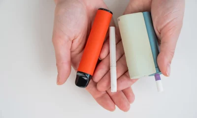 Woman holding regular, electronic cigarette and disposable vape on white background. Tobacco heating systems.