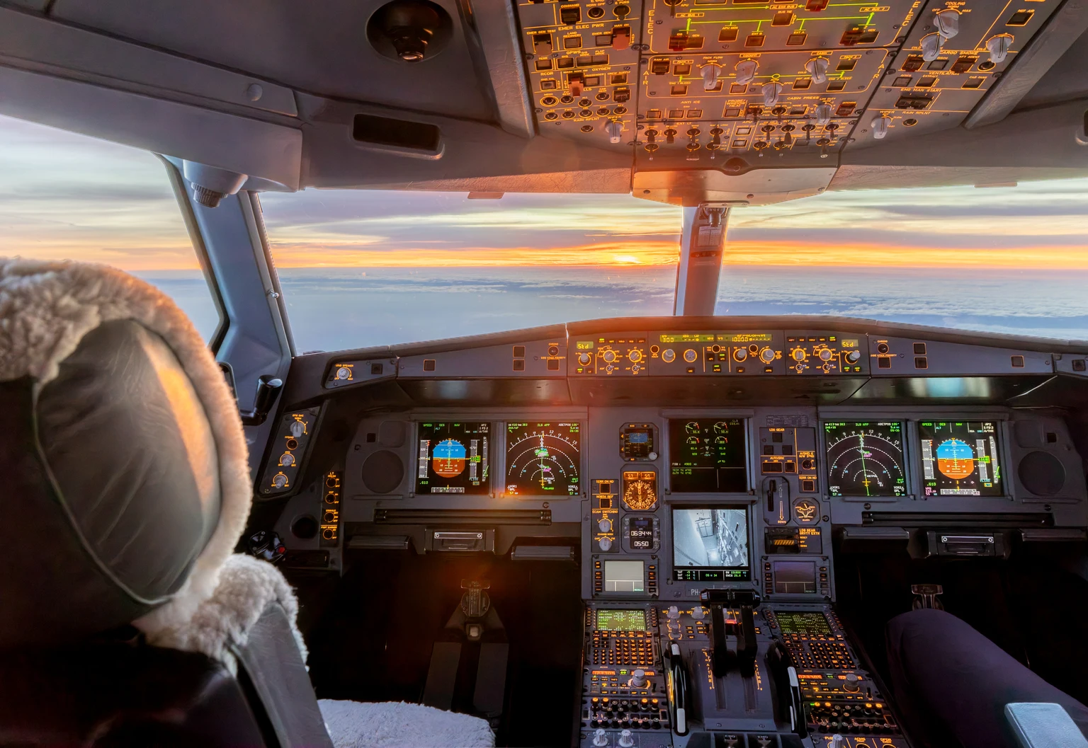 Cockpit of commercial jet illuminated at sunrise during flight