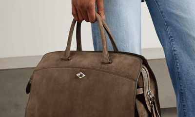 woman carries brownish suede tote