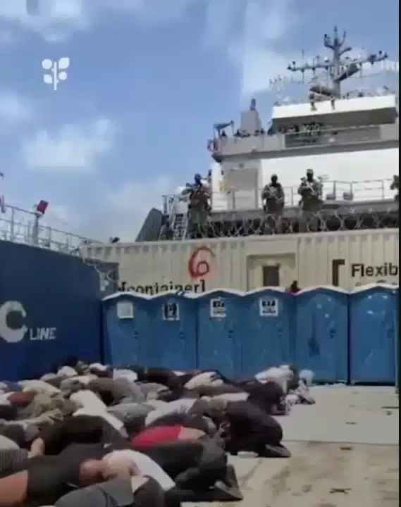 Bodies, likely of the Global Sumud Flotilla volunteers, crouch over in rows on what appears to be the deck of a ship