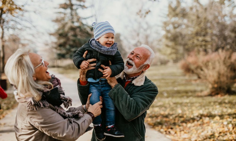 grandma and grandad lift small grandchild up in an embrace on a winter day
