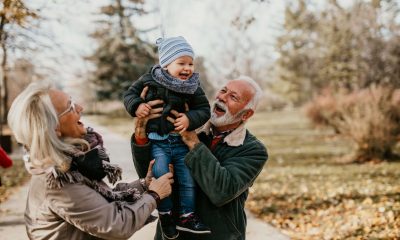 grandma and grandad lift small grandchild up in an embrace on a winter day