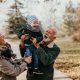 grandma and grandad lift small grandchild up in an embrace on a winter day