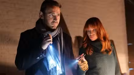Ewan Leslie and Emma Booth holding flashlights, investigating something, in The Gloaming