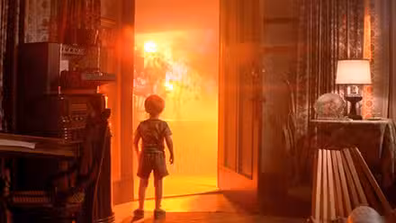 A child stares out an open front door where an ominous orange glow is coming though