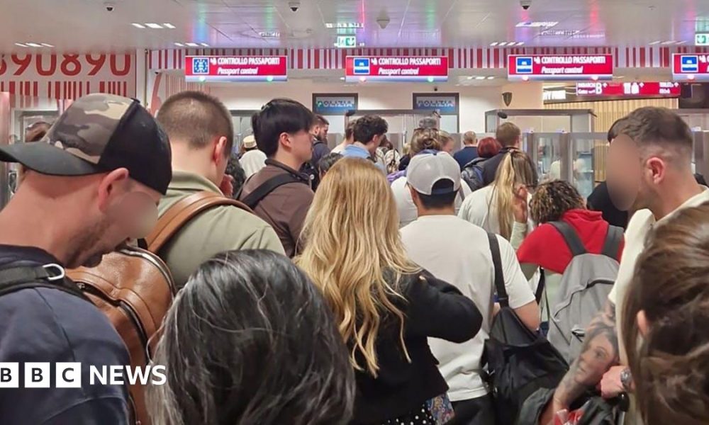 A crowd of passengers waiting in the passport control queue at Milan Bergamo airport on 16 April,  with four check-in desks visible.
