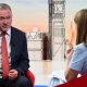 Housing, Communities and Local Government Secretary Steve Reed appearing on the Sunday with Laura Kuenssberg, with presenter Victoria Derbyshire standing in. The pair sit on red bucket chairs. Reed wears a black suit with a white shirt and a red tie. Derbyshire is wearing a pastel blue dress with short sleeves. She has shoulder length, dark blonde hair.