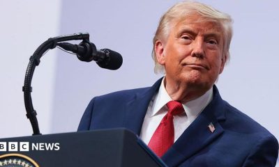 President Donald Trump speaking on stage during a press conference at the G7 Leaders' Summit