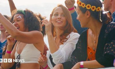Three women at a music concert wearing colourful clothes, headpieces and make-up