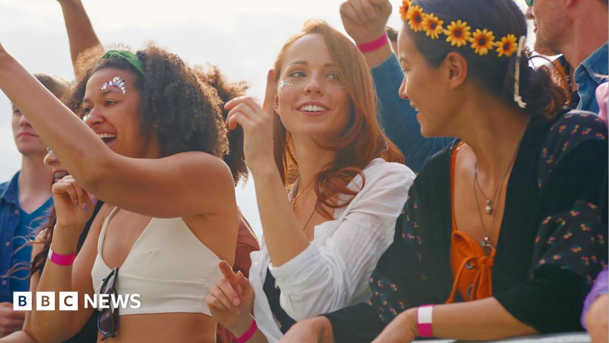 Three women at a music concert wearing colourful clothes, headpieces and make-up