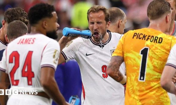 Harry Kane squirts water on his face during a hydration break in England's match against Croatia at the 2026 World Cup.