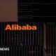 The Alibaba logo in orange lights is displayed on the exterior of an office that appears with black windows at dusk.