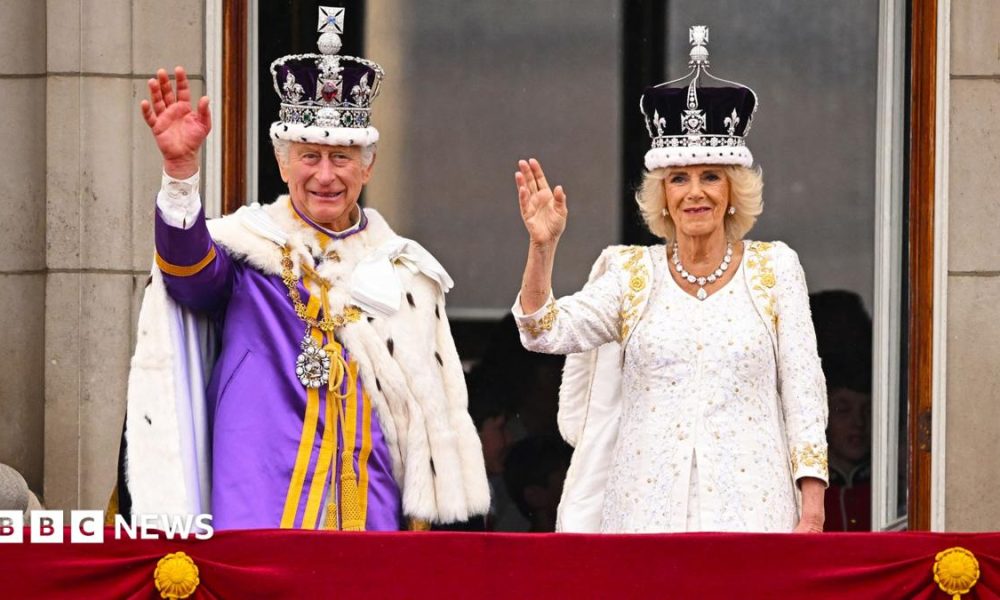 King Charles and Queen Camilla on the Buckingham Palace balcony wearing crowns and robes