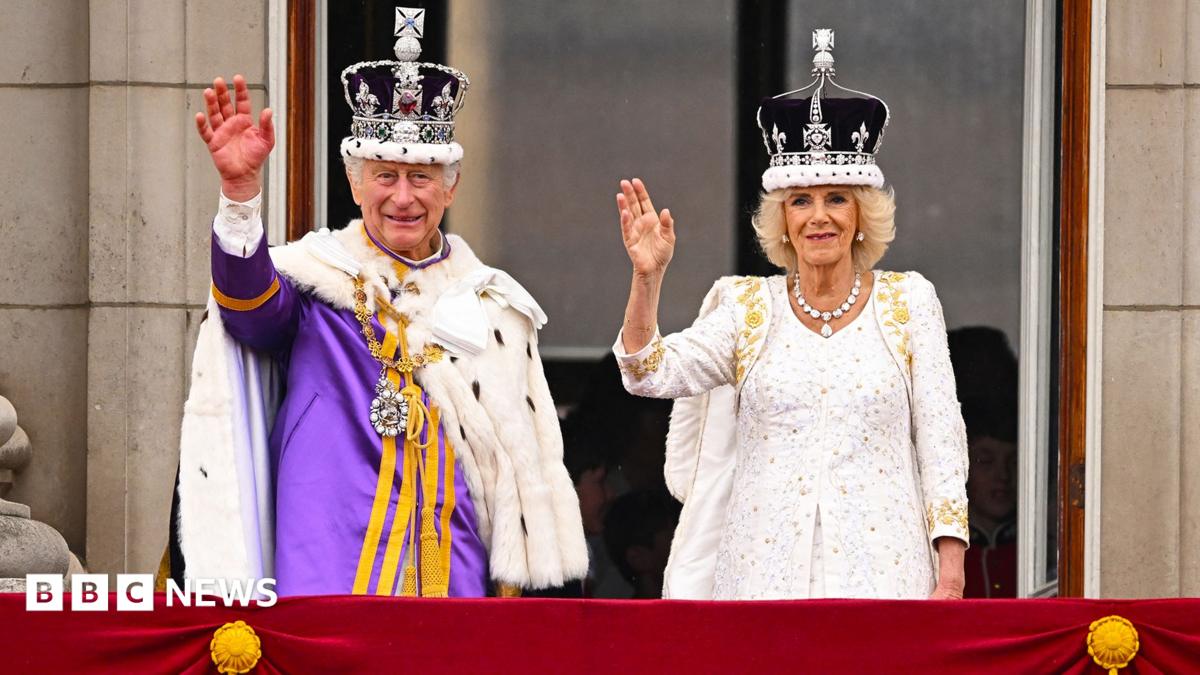 King Charles and Queen Camilla on the Buckingham Palace balcony wearing crowns and robes