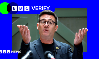 Andy Burnham holds his hands up in front of him as he delivers a speech