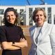 Two women standing outside federal parliament house in Canberra. One is a brunette wearing a black top and with her hands folded. The other has a short blonde bob and wearing a white blazer.