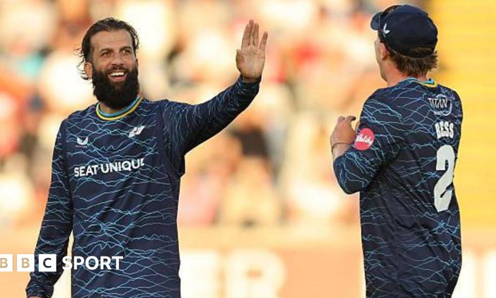 Yorkshire player Moeen Ali smiles and holds up his hand in celebration as he is approached by team-mate Dom Bess.