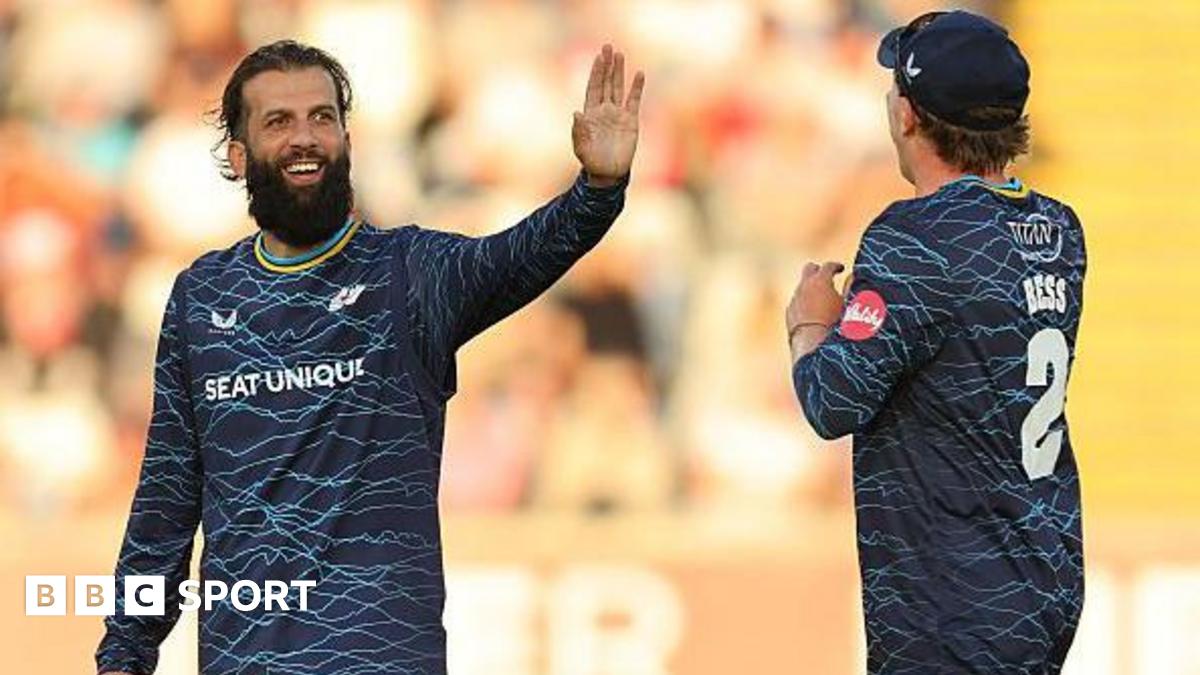 Yorkshire player Moeen Ali smiles and holds up his hand in celebration as he is approached by team-mate Dom Bess.