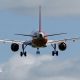 A passenger jet prepares to land at London Gatwick, near Crawley, on 20 April 2026. It is seen against a pale blue sky with fluffy clouds. The wheels are down for landing.