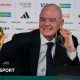 FIFA president Gianni Infantino, in dark suit and tie and white shirt, speaks next to the World Cup trophy and a football during a news conference on the eve of the opening match of the 2026 World Cup