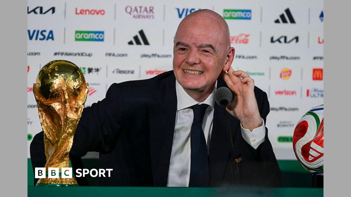 FIFA president Gianni Infantino, in dark suit and tie and white shirt, speaks next to the World Cup trophy and a football during a news conference on the eve of the opening match of the 2026 World Cup