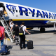 Passengers incluidng children boarding a Ryanair aircraft using the steps at the front of the plane on a sunny day with blue skies