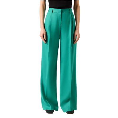 A woman (lower half of body shown) wearing green pants, a black top, and black flats