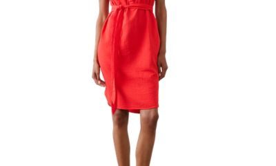 A woman wearing a red/orange shirtdress and off-white flats