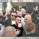 Tommy Robinson in a crowd speaking into a microphone, surrounded by people and cameras, before the riot kicked off