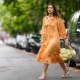 PARIS, FRANCE - MAY 10: Ketevan Giorgadze @katie.one wears gold earrings, a long buttoned coral loungewear linen The Sleeper dress with puffy sleeves, gold rings, a wicker with brown shiny leather detail Le Panier Soleil Jacquemus tote-bag, white strappy low heeled Raye sandals, on May 10, 2021 in Paris, France. (Photo by Edward Berthelot/Getty Images)