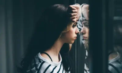 Stock image of girl looking through window, illustrating mental health outcomes